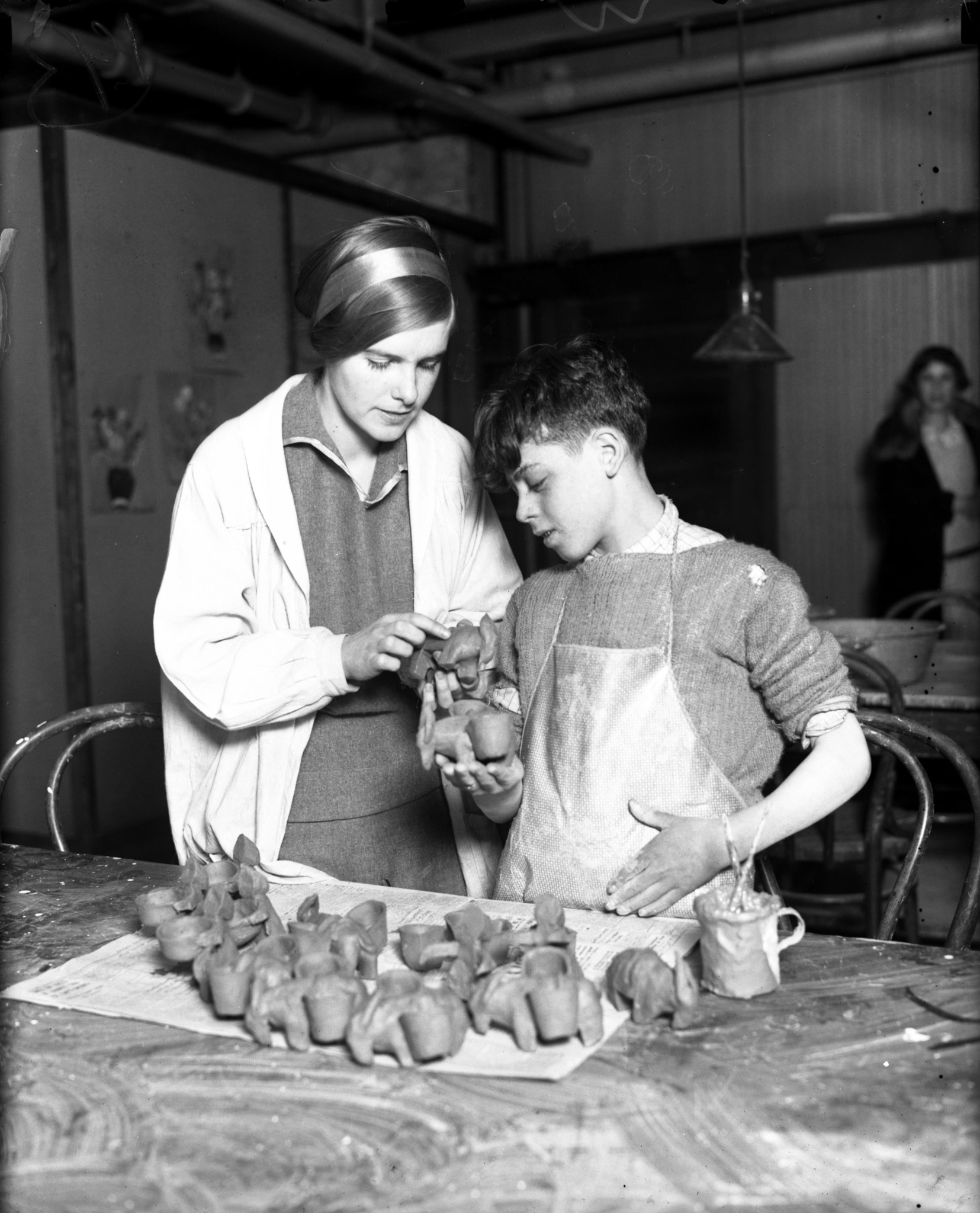 Pottery class teacher Evangeline Wallace helps student Domminick Randazzo make...