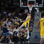 Oct 4, 2024; Palm Desert, California, USA; Los Angeles Lakers guard Dalton Knecht (4) hangs on the rim after dunking against Minnesota Timberwolves center Jesse Edwards (14) during the second half at Acrisure Arena. Mandatory Credit: Jonathan Hui-Imagn Images