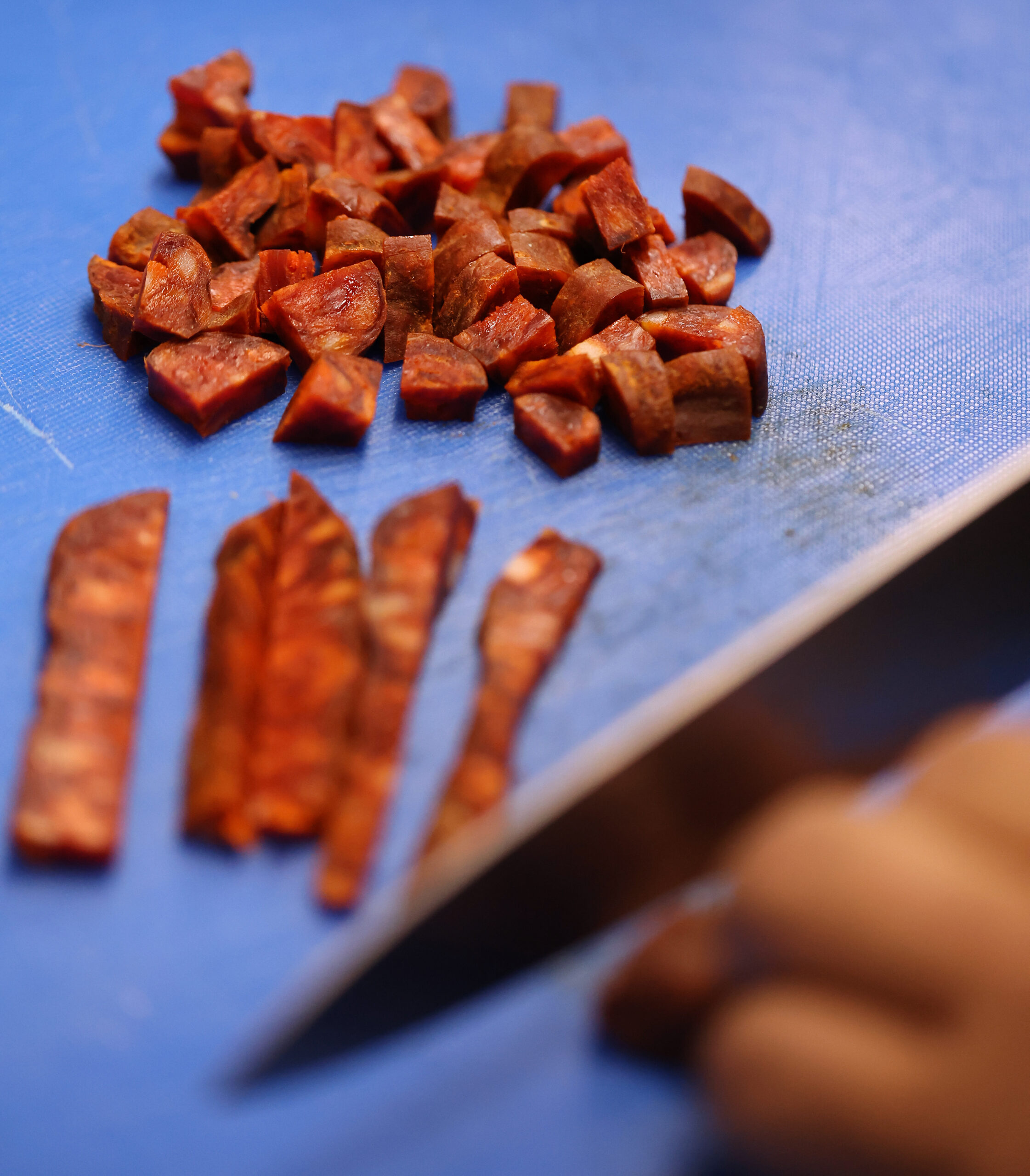 Chef Marcos Asencio cuts up chorizo to be used in...