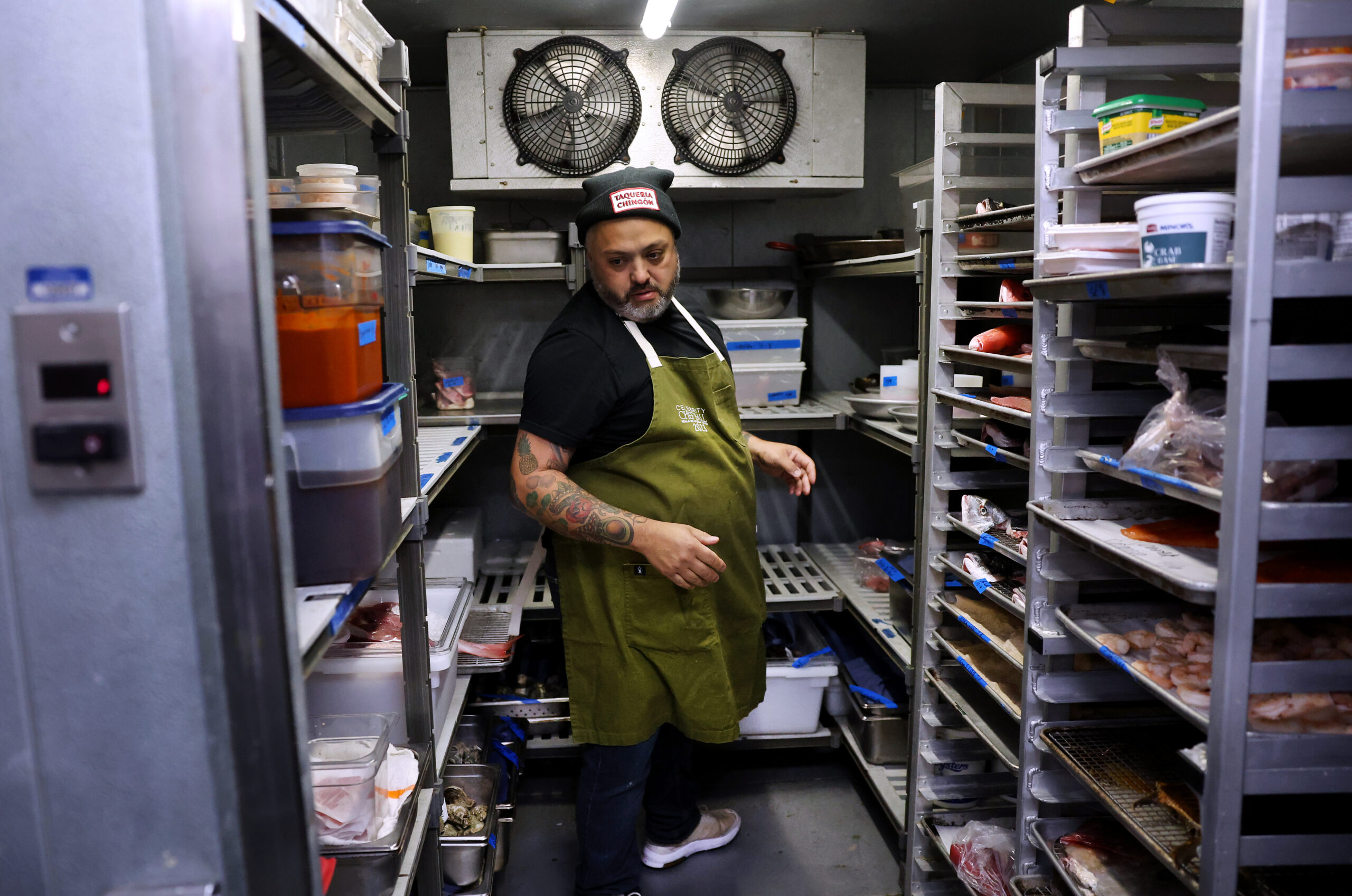 Chef Marcos Asencio scans a cooler while prepping in the...