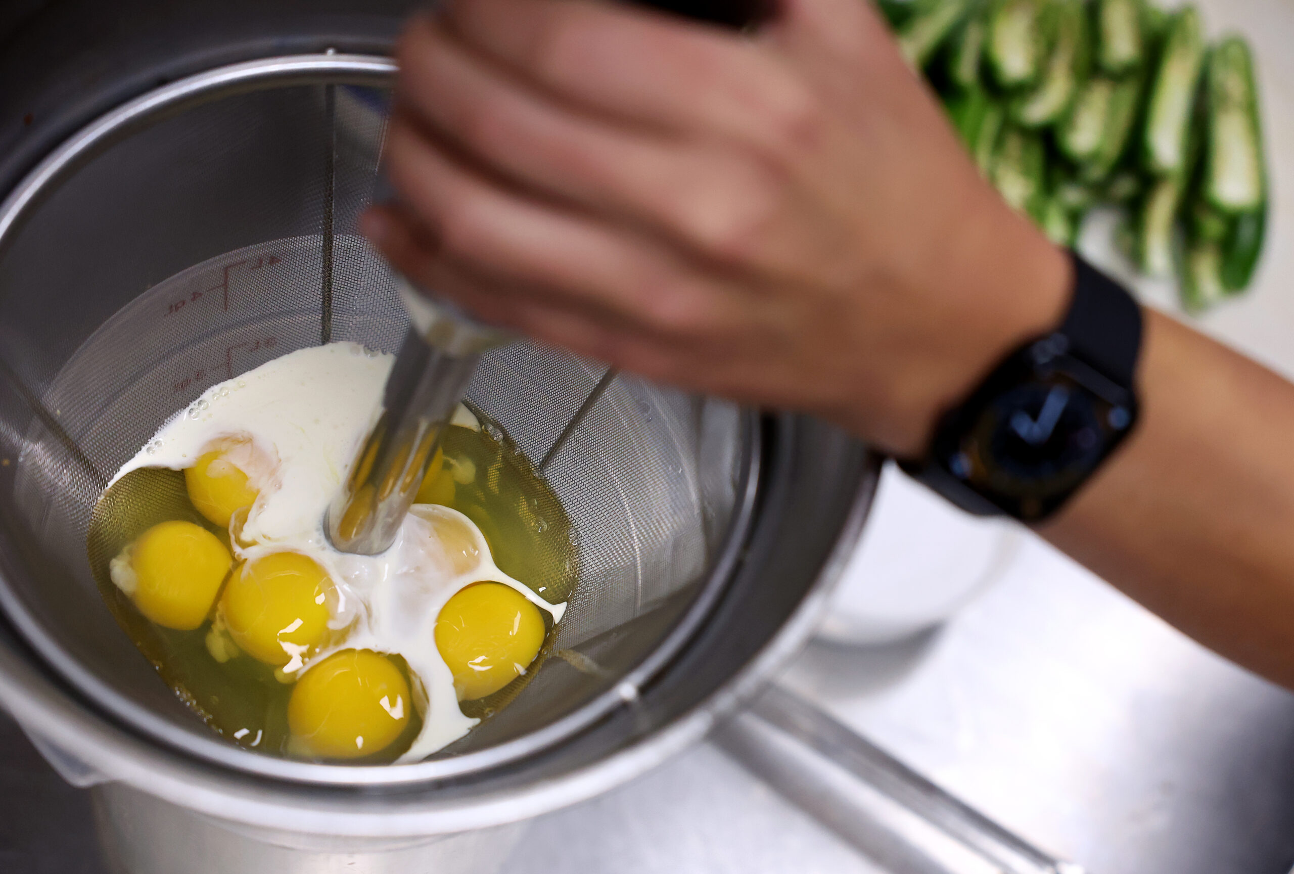 Alex Martinez uses an immersion blender to mix eggs and...