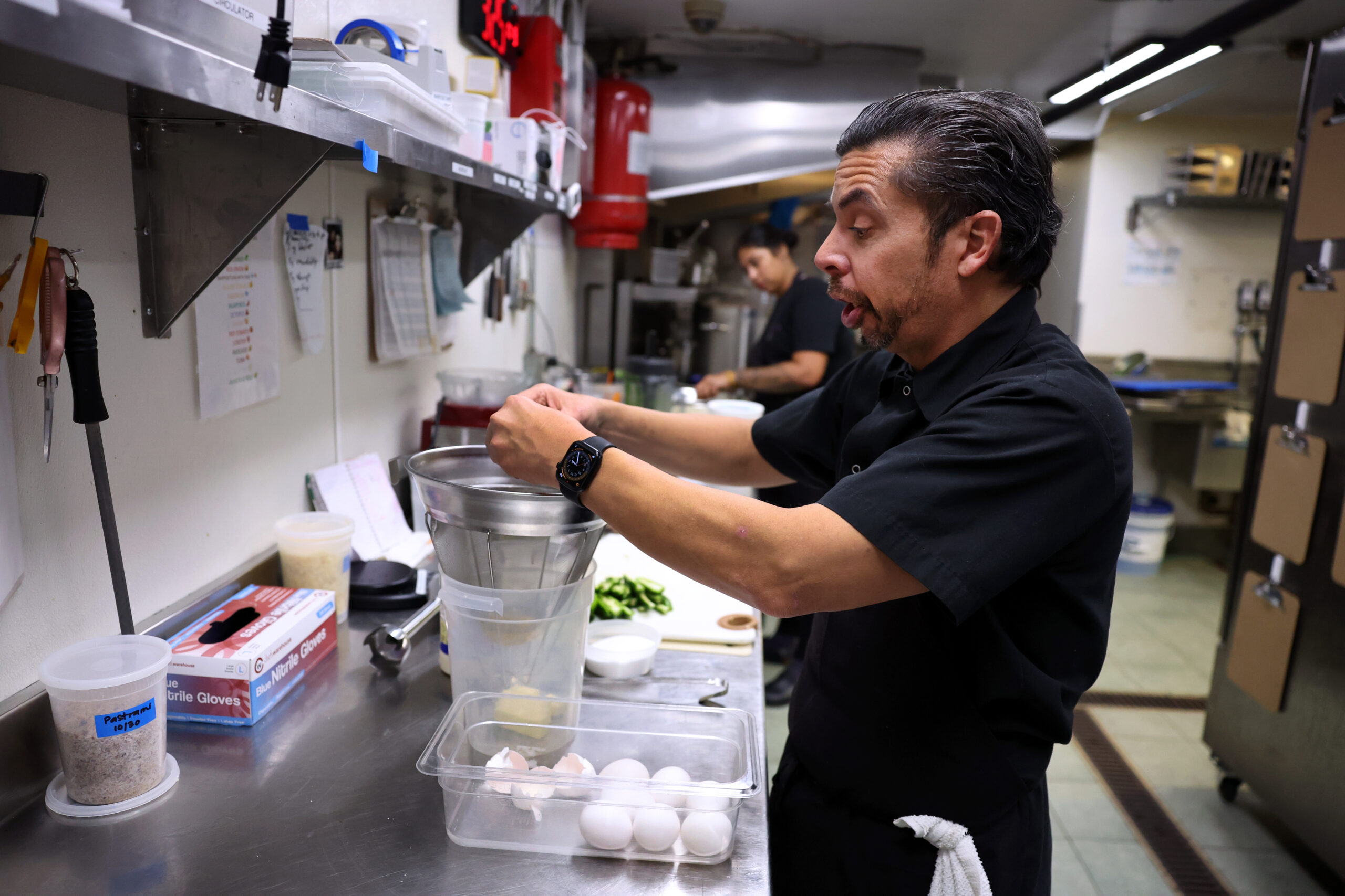 Alex Martinez breaks eggs for a French scramble dish while...