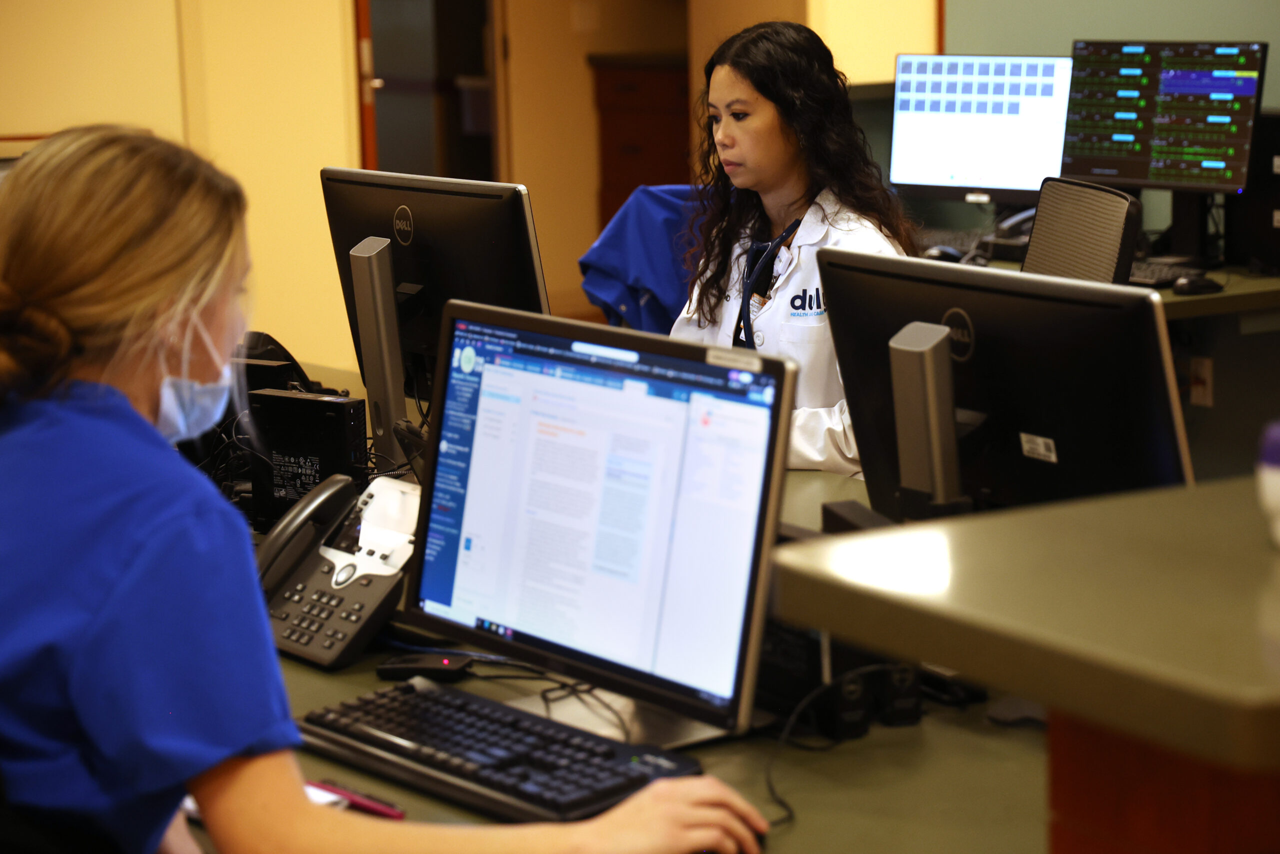 Nurses look over patient information on computers at Endeavor Health...