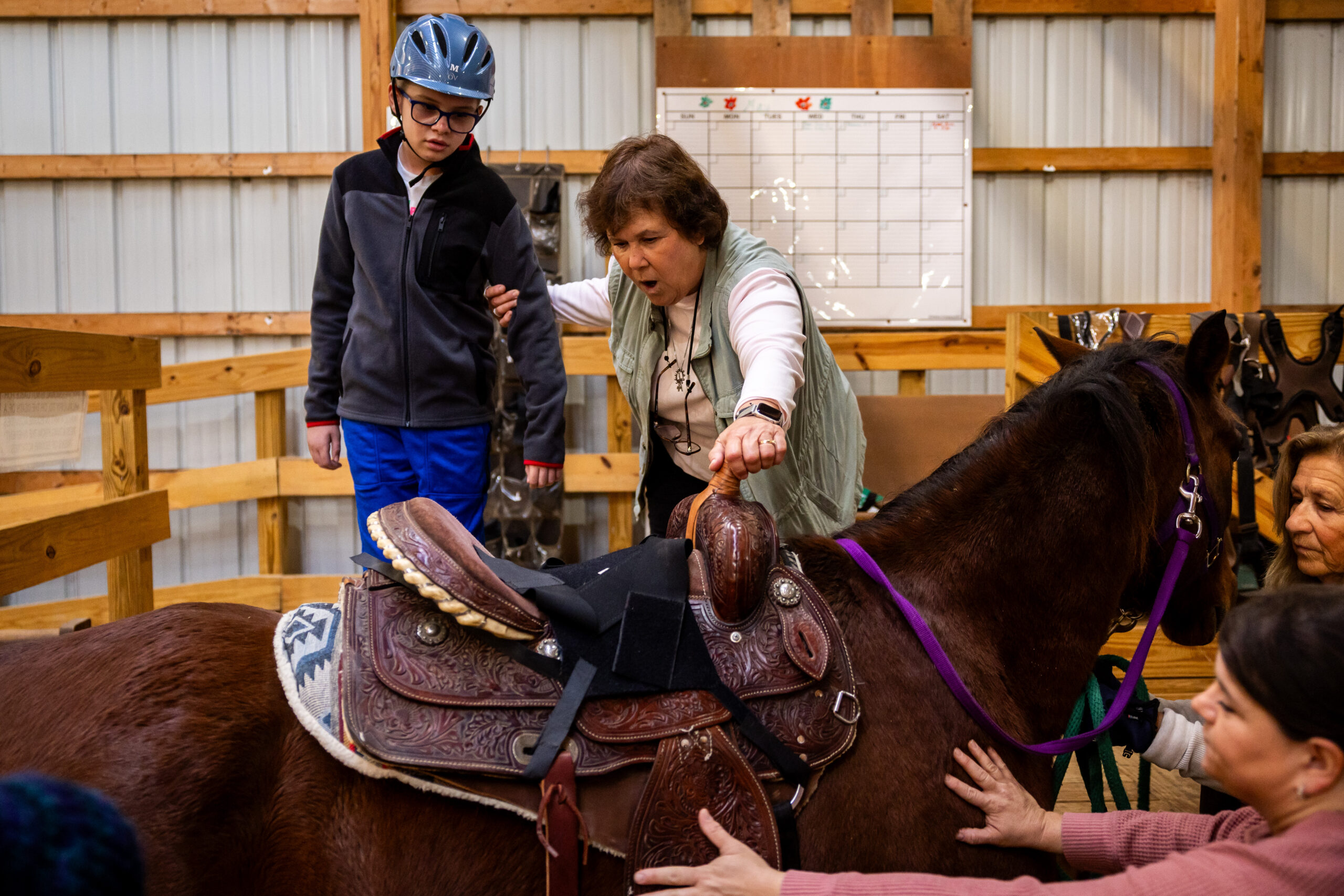 Cindy Sauer, center, helps Liam Bullington, 12, left, who lives...