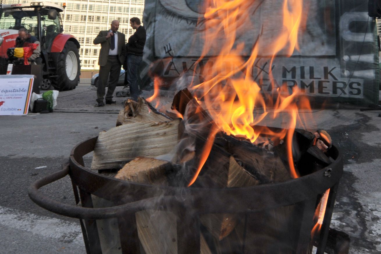 A garbage can burns as tractors belongin